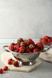 Photo of Metal colander with fresh strawberries on grey countertop