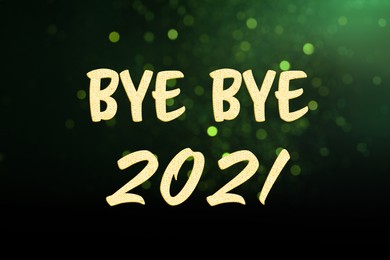 Phrase Bye Bye 2021 on green background with blurred festive lights. Bokeh effect