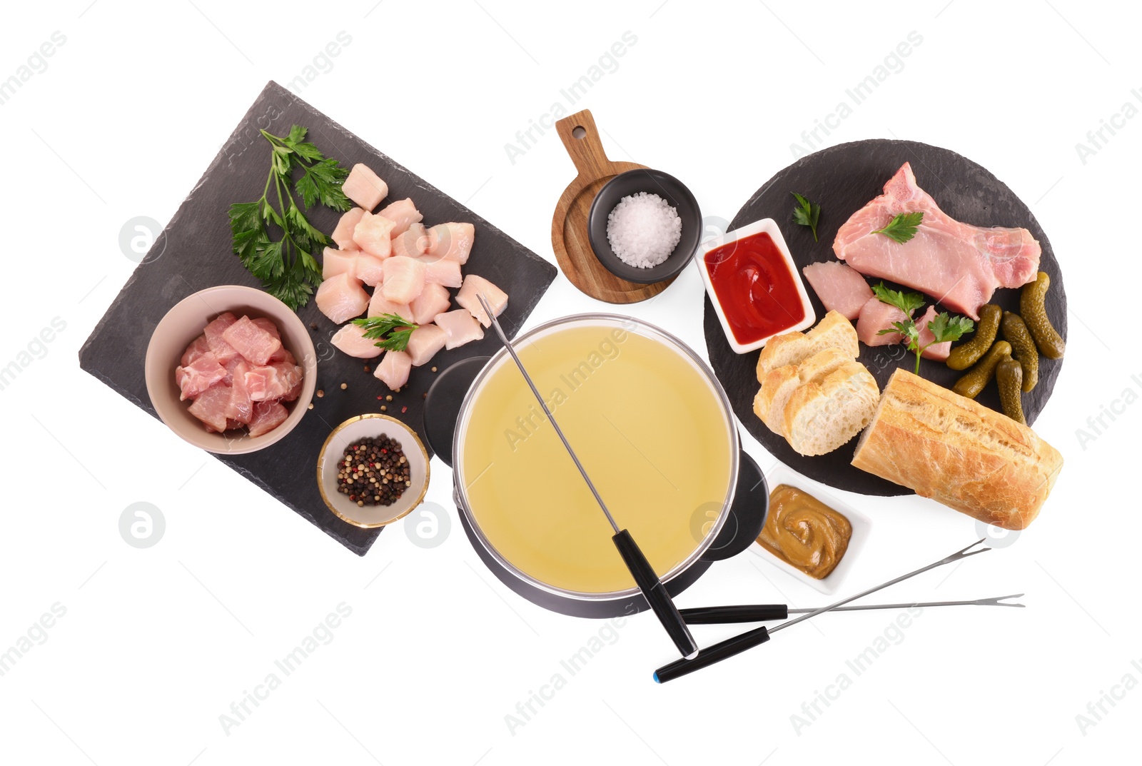 Photo of Oil in fondue pot, forks, sauces, pieces of raw meat and other products isolated on white, top view