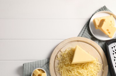 Photo of Grated and whole pieces of cheese on white wooden table, flat lay. Space for text