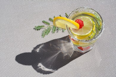 Photo of Delicious refreshing lemonade with raspberries on light gray rattan surface, above view