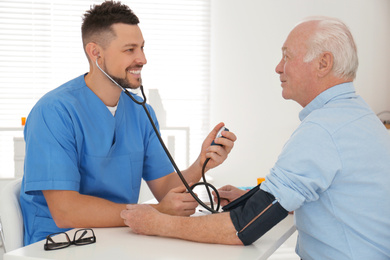 Doctor measuring blood pressure of senior patient in office