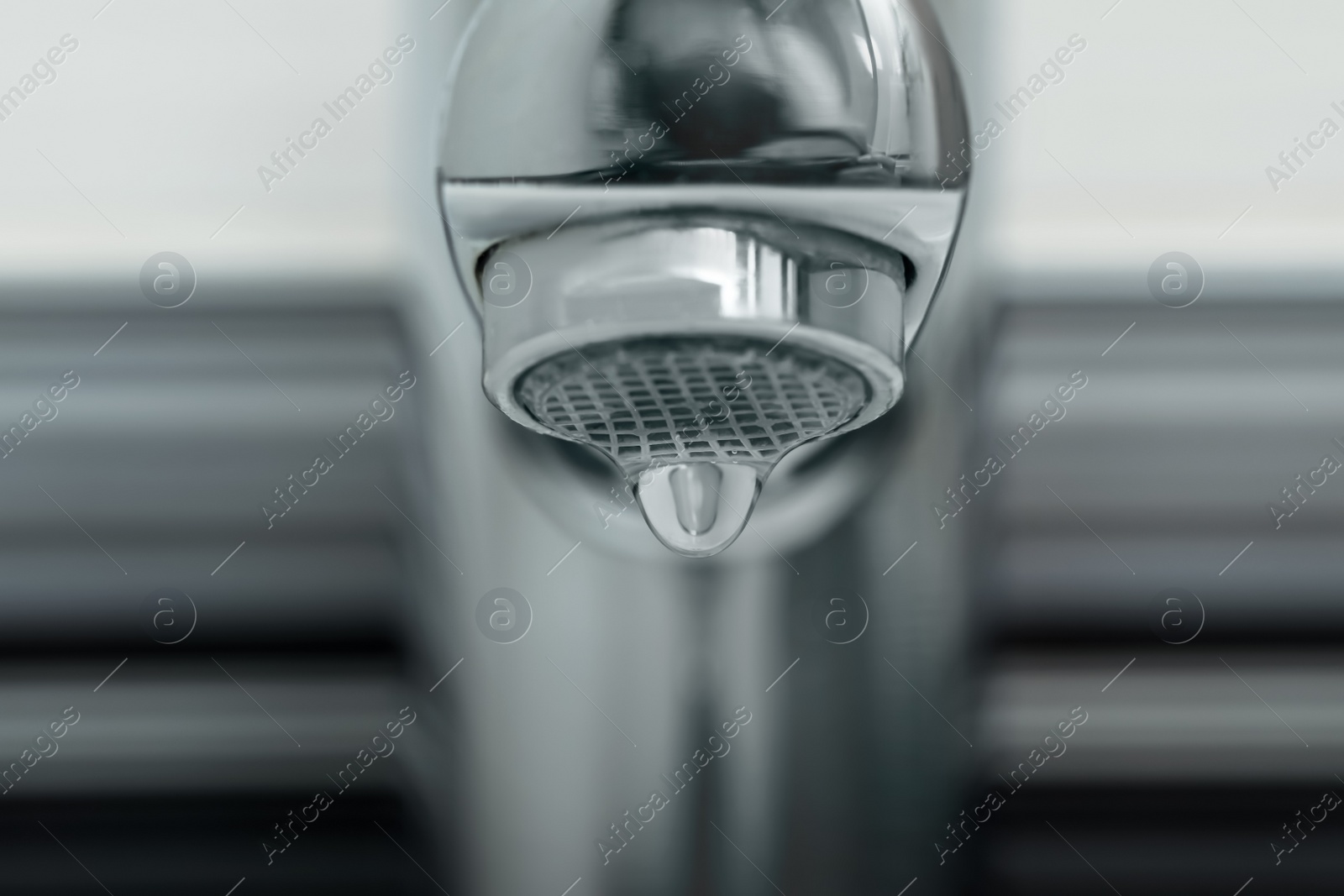 Photo of Water drop falling down from tap on blurred background, closeup