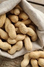 Fresh unpeeled peanuts in sack on wooden table