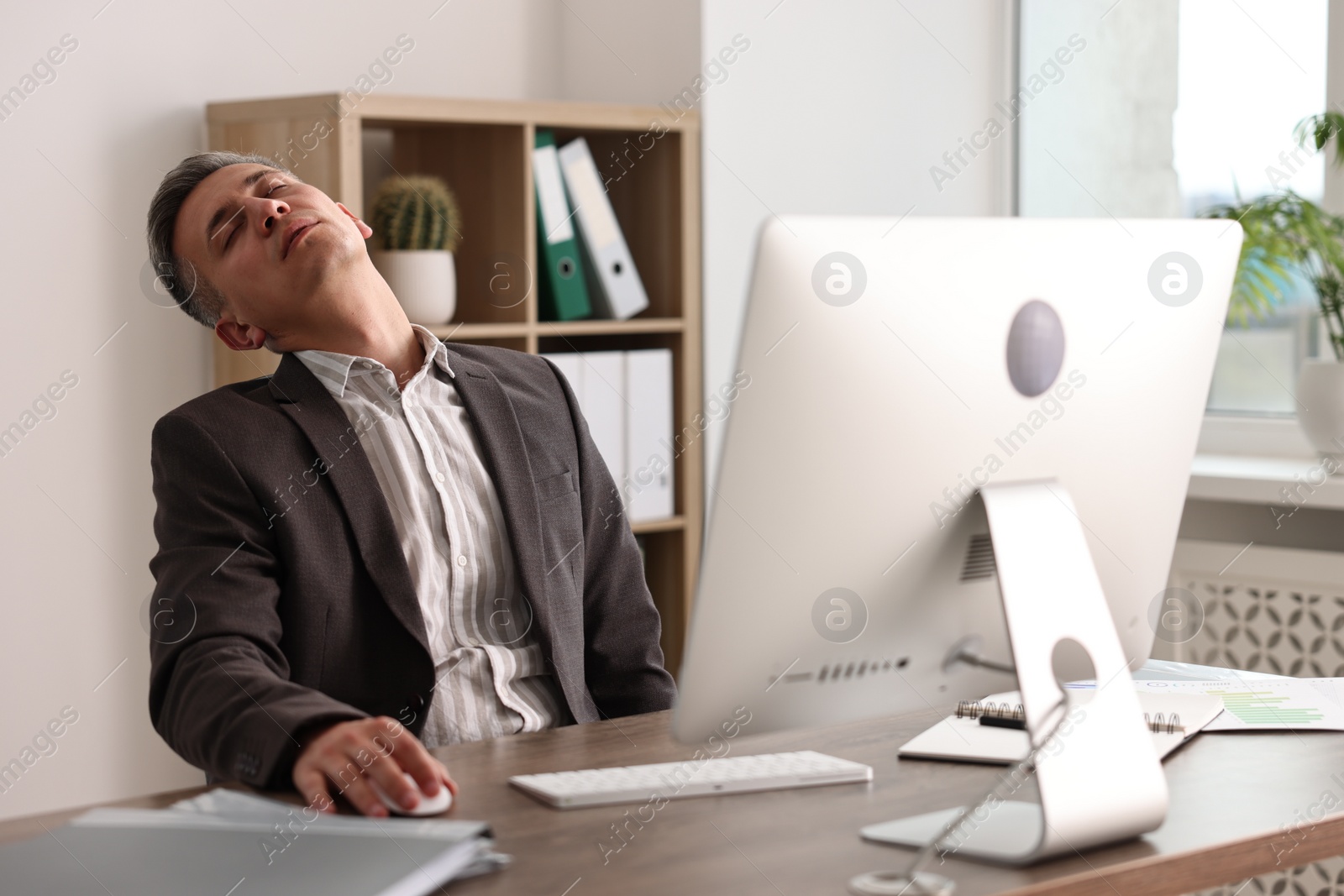 Photo of Man snoozing at wooden table in office