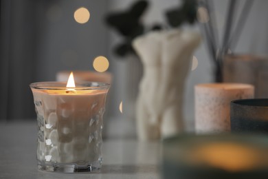 Beautiful burning candle on white table in room, space for text