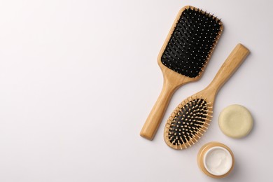 Photo of Wooden hairbrushes and cosmetic products on white background, flat lay. Space for text