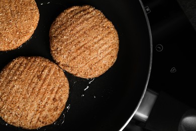 Photo of Cooking vegan cutlets in frying pan on cooktop, closeup