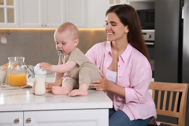 Happy young woman with her cute little baby in kitchen