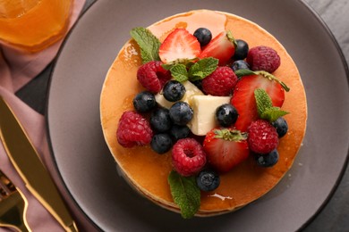 Photo of Delicious pancakes with fresh berries, honey and butter served on table, top view