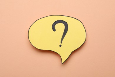 Paper speech bubble with question mark on beige background, top view