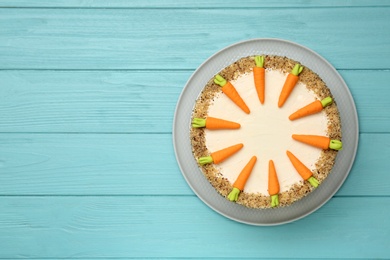 Dish with delicious carrot cake on blue wooden background, top view. Space for text