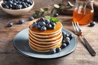 Plate with pancakes and berries on wooden table