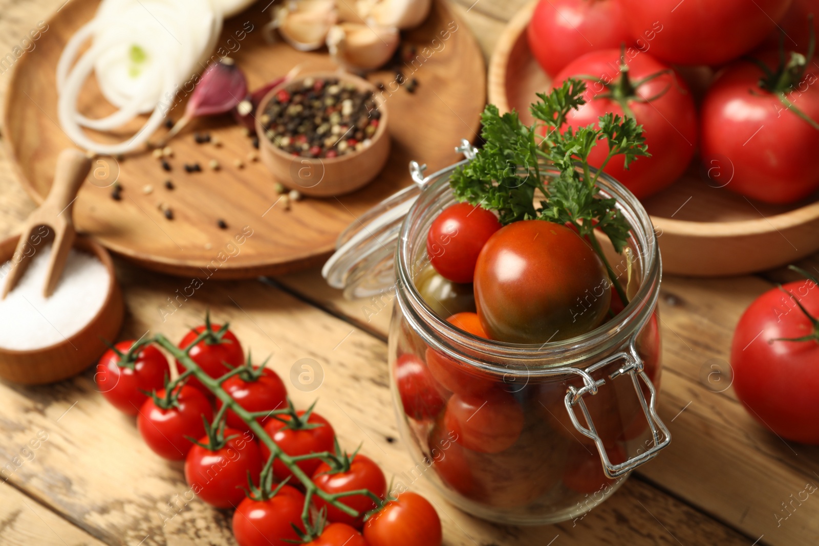 Photo of Pickling jar with fresh ripe cherry tomatoes and spices on wooden table