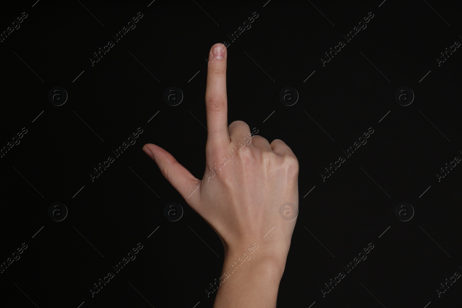 Photo of Woman pointing at something on black background, closeup. Finger gesture