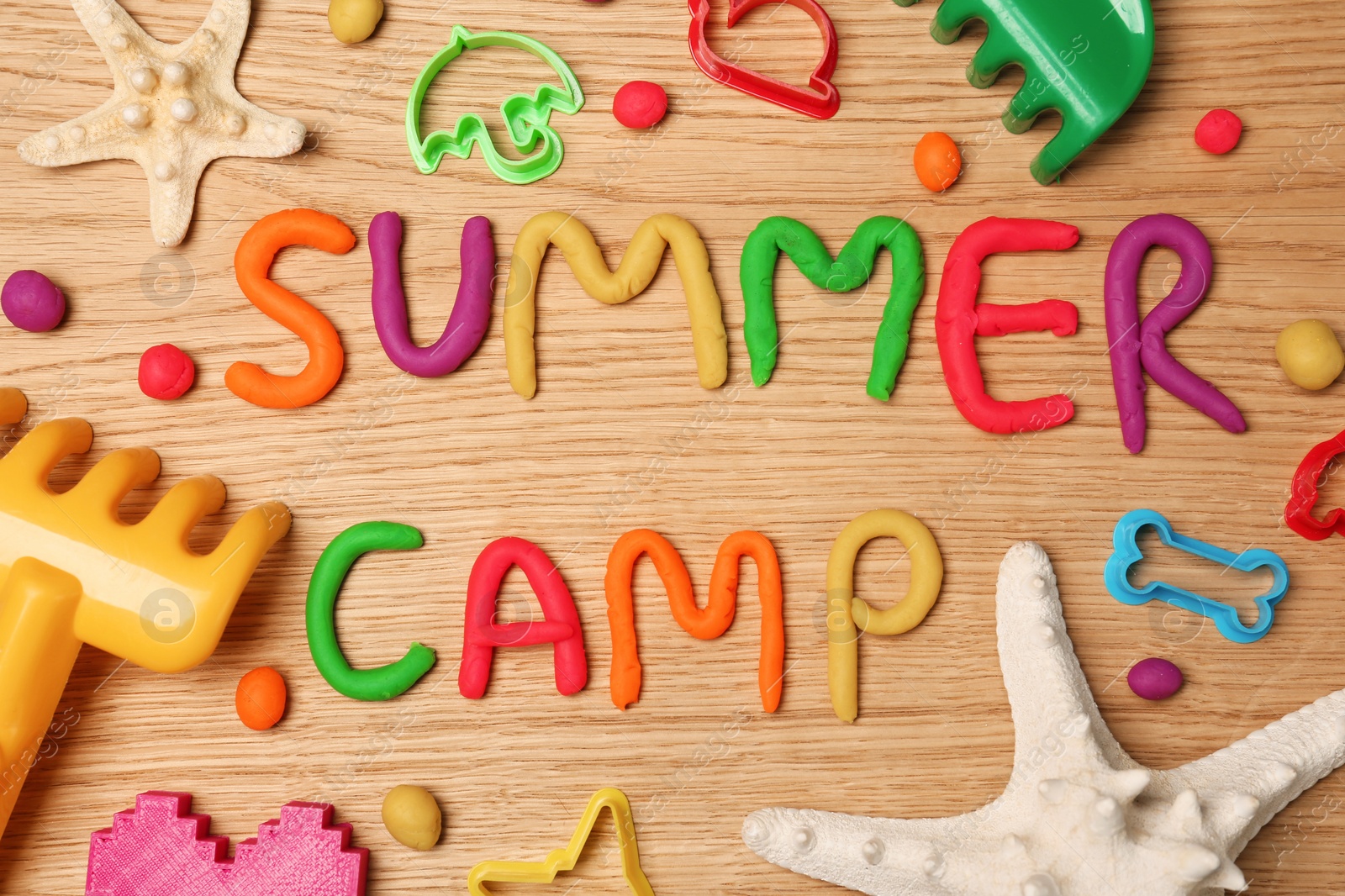 Photo of Text SUMMER CAMP made with play dough on wooden background, top view