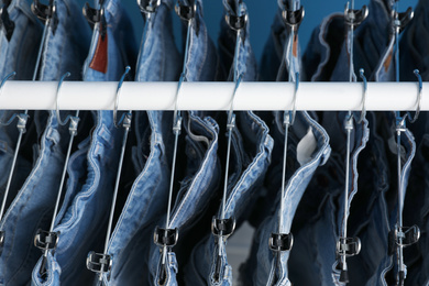 Hangers with stylish jeans on rack, above view