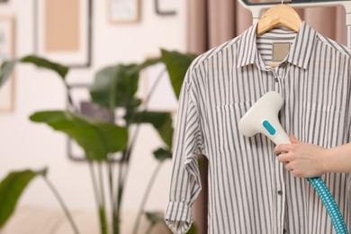 Photo of Woman steaming shirt on hanger at home, closeup. Space for text