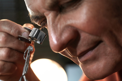 Photo of Professional jeweler evaluating beautiful ring, closeup view