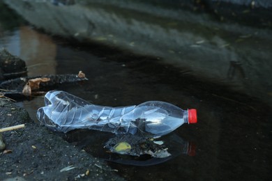 Used plastic bottle near water outdoors. Environment pollution