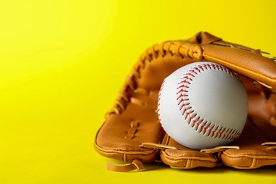 Catcher's mitt and baseball ball on yellow background, space for text. Sports game