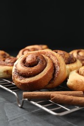 Photo of Tasty cinnamon rolls on black table, closeup. Space for text