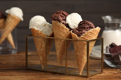 Photo of Tasty ice cream scoops in waffle cones on wooden table, closeup