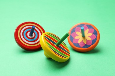 Photo of Many colorful spinning tops on green background, closeup