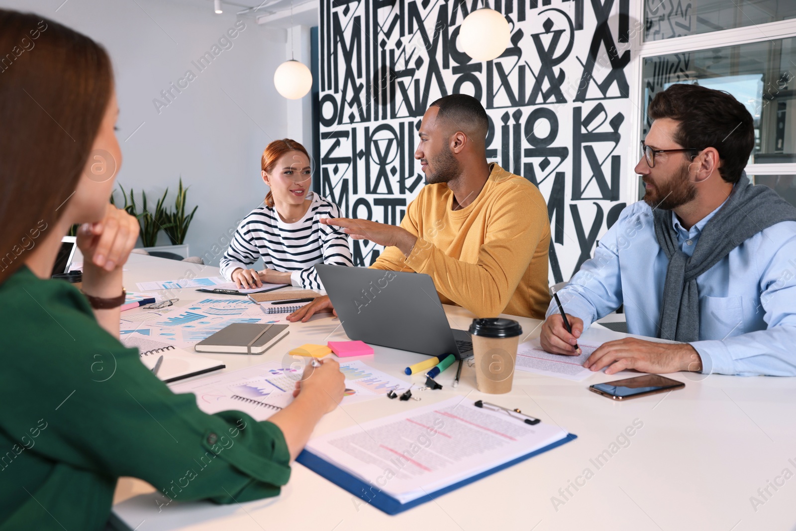 Photo of Team of employees working together at table in office. Startup project