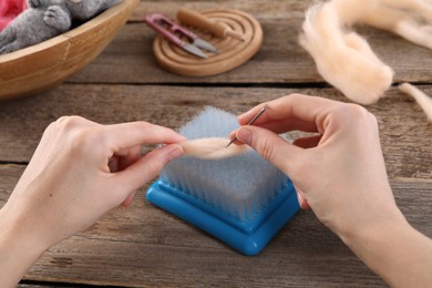 Photo of Woman felting from wool at wooden table, closeup