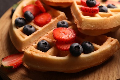 Tasty Belgian waffles with fresh berries on wooden board, closeup