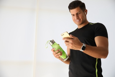 Photo of Man with smartphone and fitness tracker indoors. Space for text