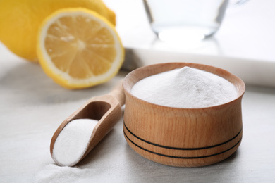 Photo of Pure baking soda and cut lemons on white wooden table
