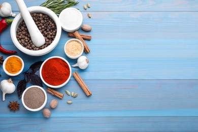 Flat lay composition with mortar and different spices on light blue wooden table, space for text