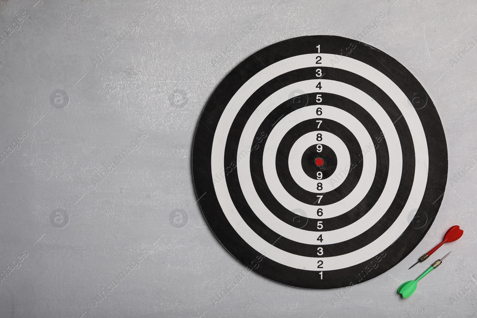 Photo of Dart board with color arrows on light stone background, top view. Space for text