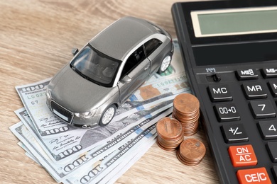 Toy car, money and calculator on table. Vehicle insurance
