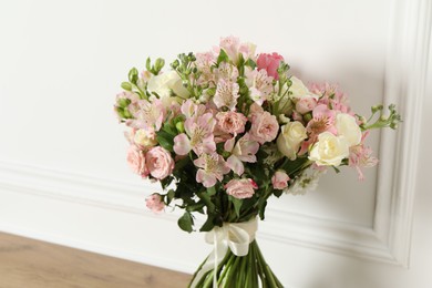 Beautiful bouquet of fresh flowers on wooden table near white wall