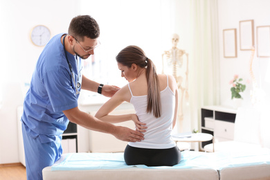 Photo of Male orthopedist examining patient's back in clinic