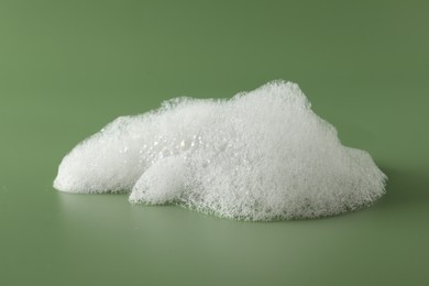 Photo of Fluffy bath foam on olive background. Care product