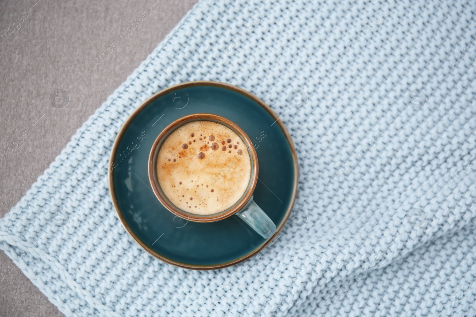 Photo of Cup of coffee and plaid on grey background, top view