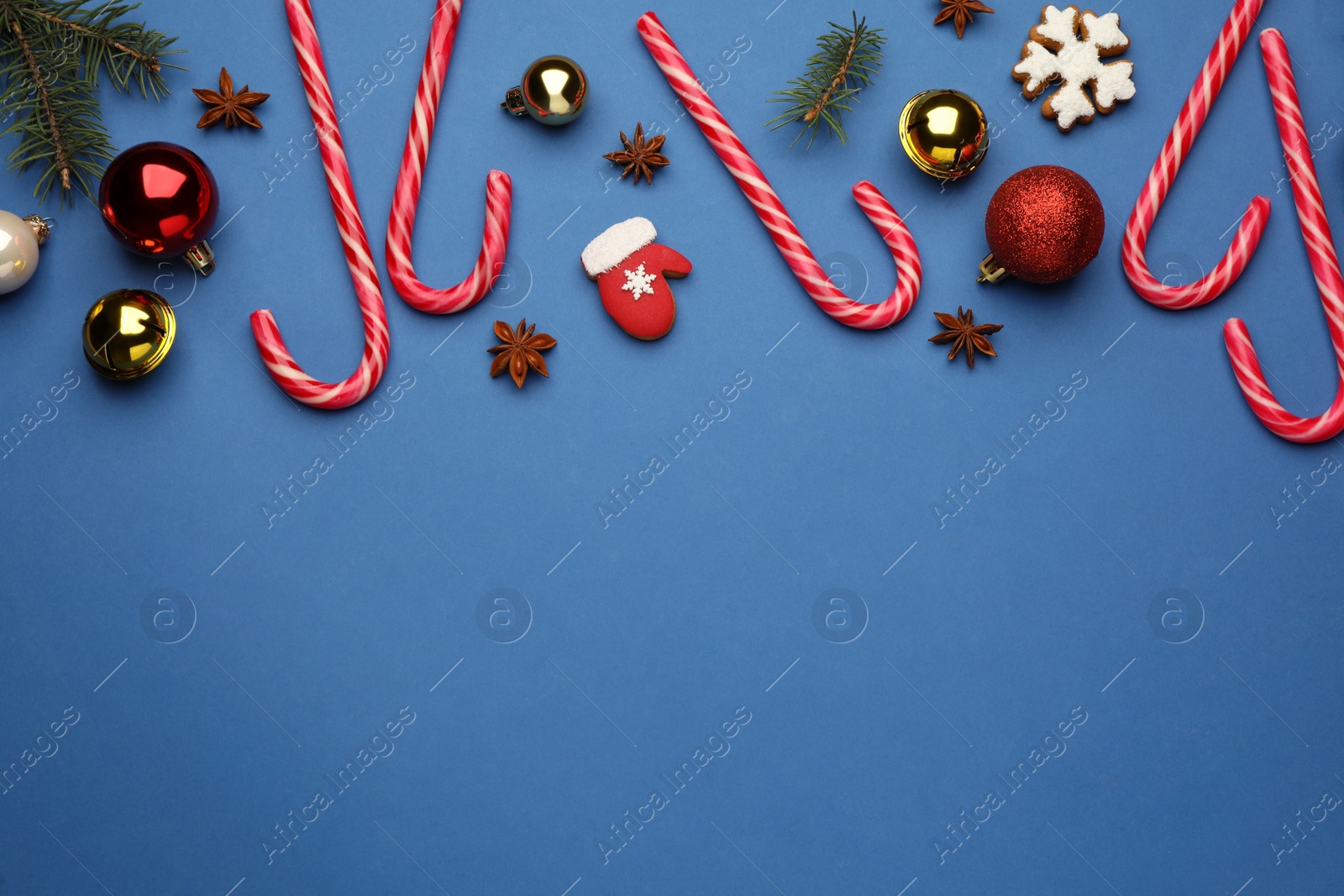 Photo of Flat lay composition with sweet candy canes and Christmas decor on blue background, space for text