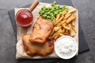 Tasty fish, chips, sauces and peas on grey table, top view