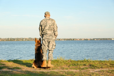 Photo of Man in military uniform with German shepherd dog outdoors