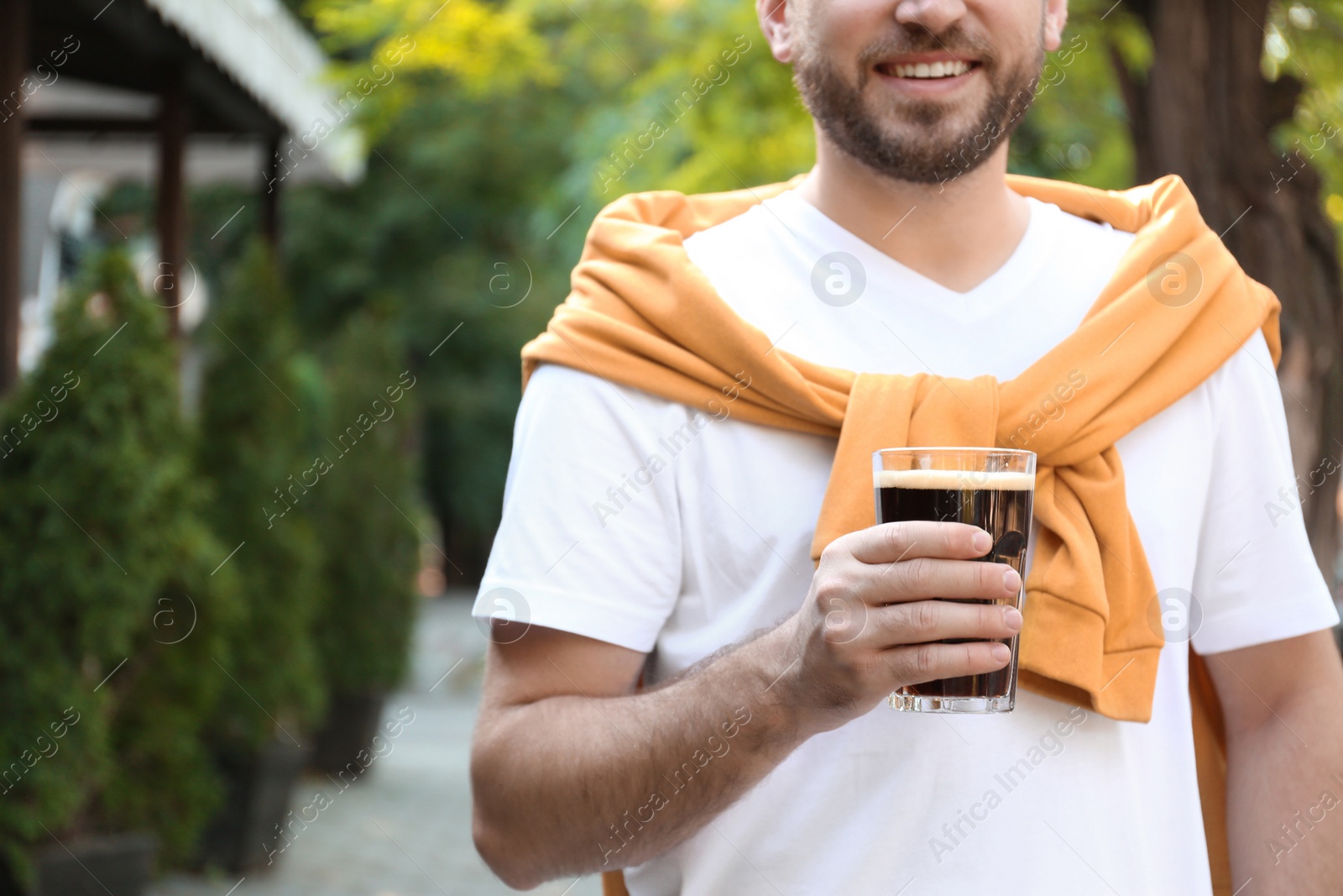 Photo of Young man with cold kvass outdoors, closeup. Traditional Russian summer drink