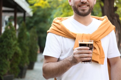 Photo of Young man with cold kvass outdoors, closeup. Traditional Russian summer drink