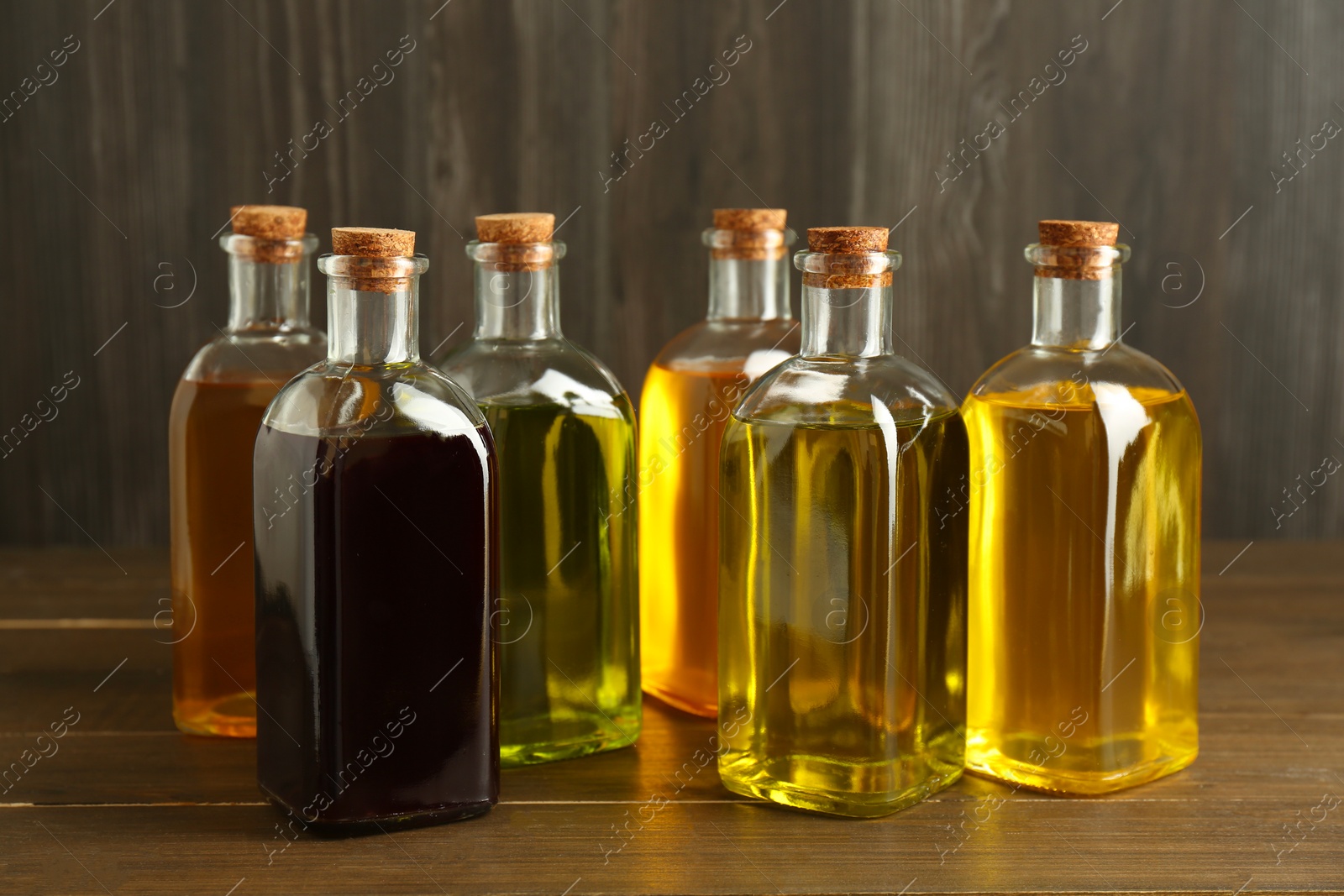 Photo of Vegetable fats. Different oils in glass bottles on wooden table