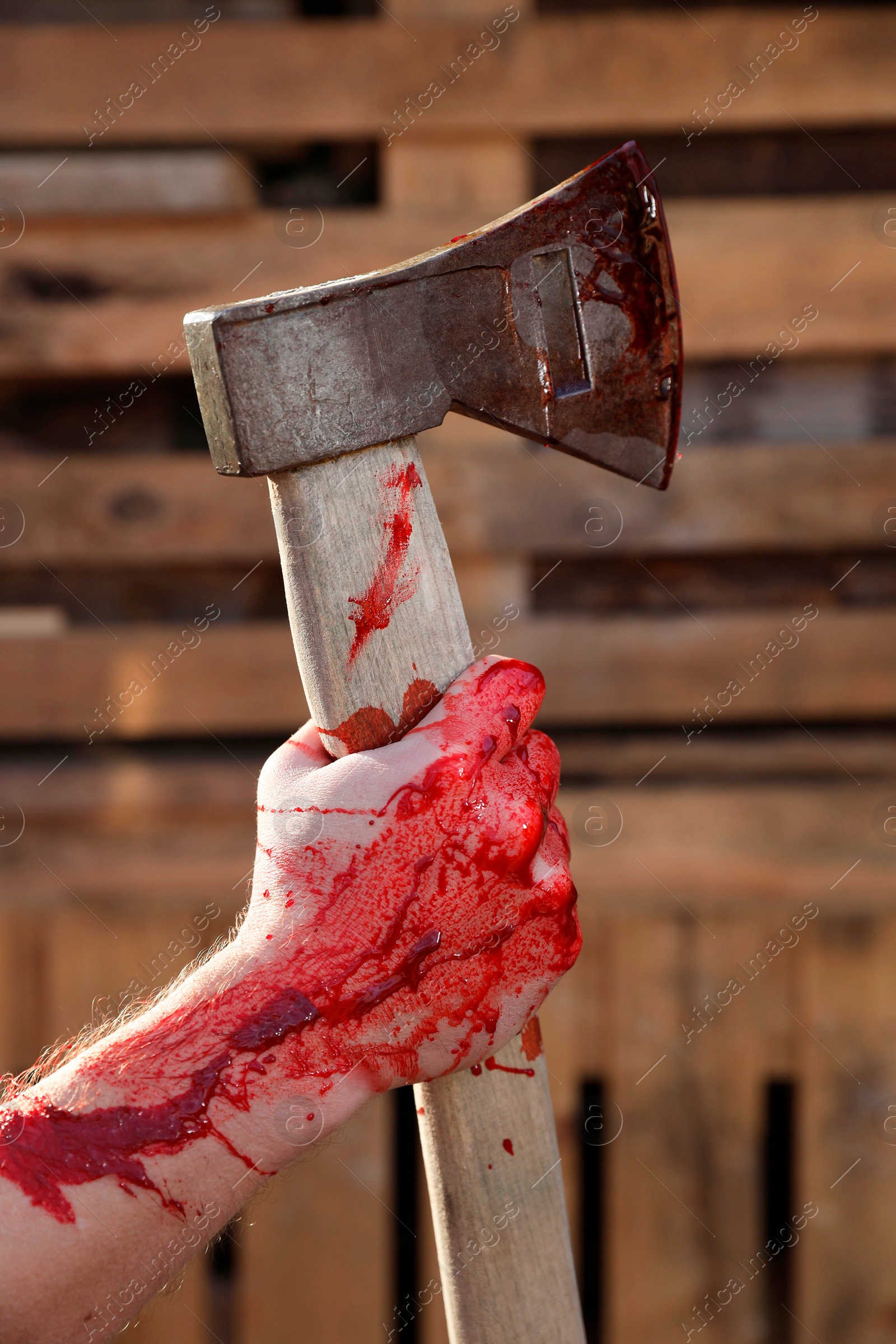 Photo of Man holding bloody axe outdoors, closeup view