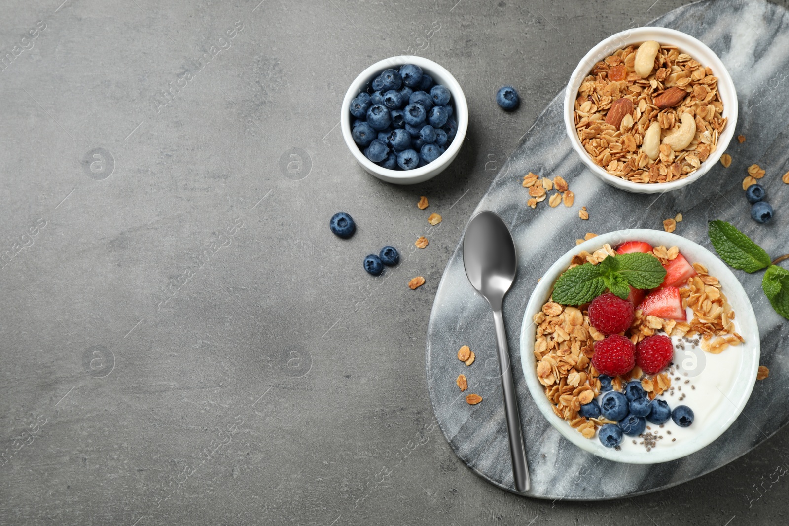 Photo of Healthy homemade granola with yogurt on grey table, flat lay. Space for text