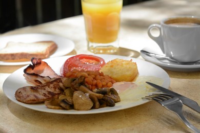 Photo of Delicious breakfast with fried meat and vegetables served on beige table, closeup