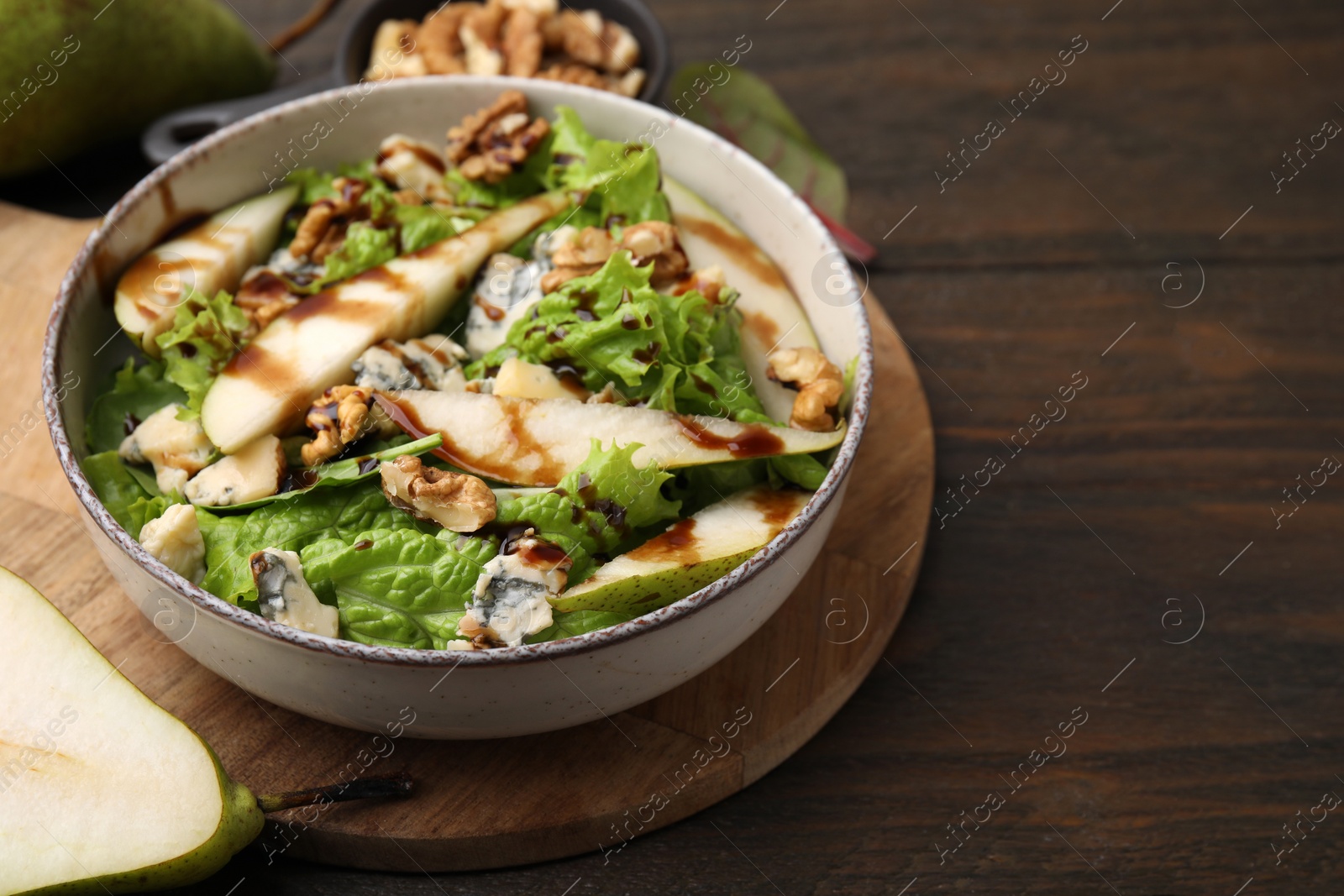 Photo of Delicious pear salad with sauce in bowl on wooden table, closeup. Space for text